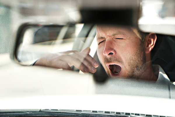 man yawning in his car because he's so tired