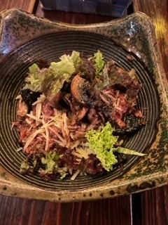 Plate of beet risotto with mushrooms and mixed greens on top