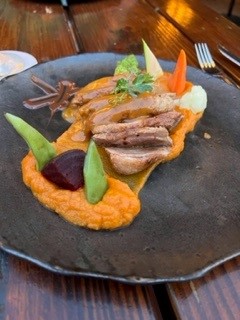 Plate of duck breast on a bed of sweet potato puree and vegetables