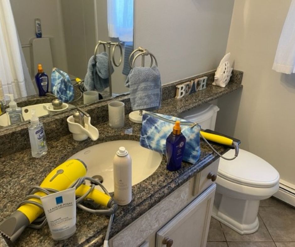 Bathroom sink with hair products and blow dryer on it