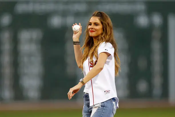 Picture of Maria Menunos throwing out the first pitch wearing a Red Sox jersey and jeans