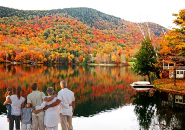 The backs of a family looking over a like to the fall foliage