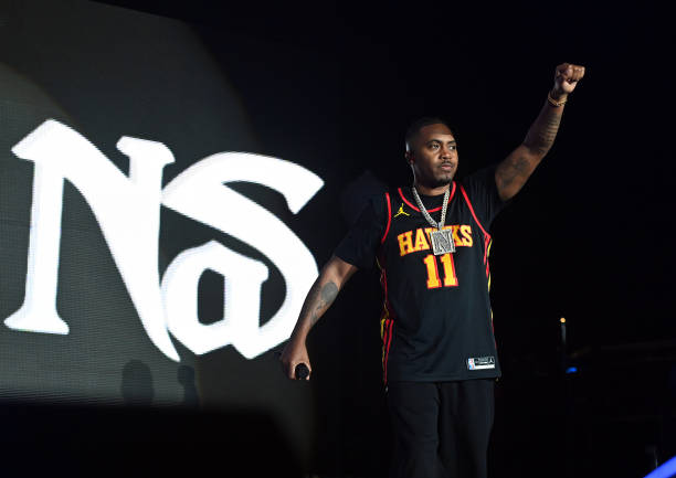 Picture of Nas with his arm in the air wearing an Atlanta Hawks jersey on