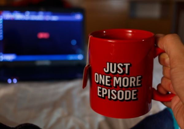 Hand holding a red cup of tea that says "just one more episode"