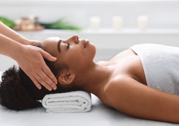 Black woman with head on towel getting a head massage