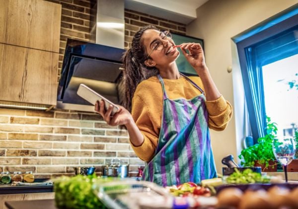 Woman smiling holding a phone and cooking