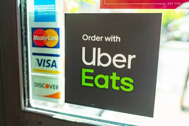 An Uber Eats sign on a window with American Express, MasterCard, Visa, and Discover stickers