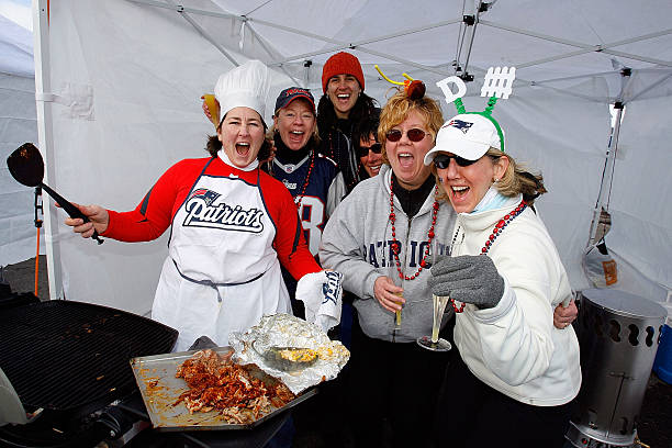 Group of six Patiots fans tailgating before a game.  