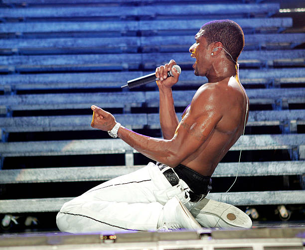 Usher shirtless singing on stage on his knees