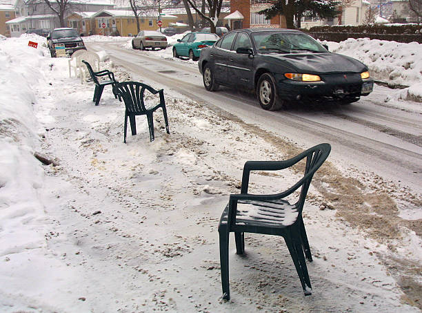 Lawn chairs on the side of the road as space savers for shoveled out parking spots. 