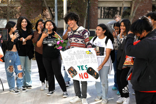 Group of teenagers with one boy holding a sign asking Cardi B to go to homecoming with him.